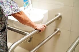 A woman is standing in a bathroom with a handrail.